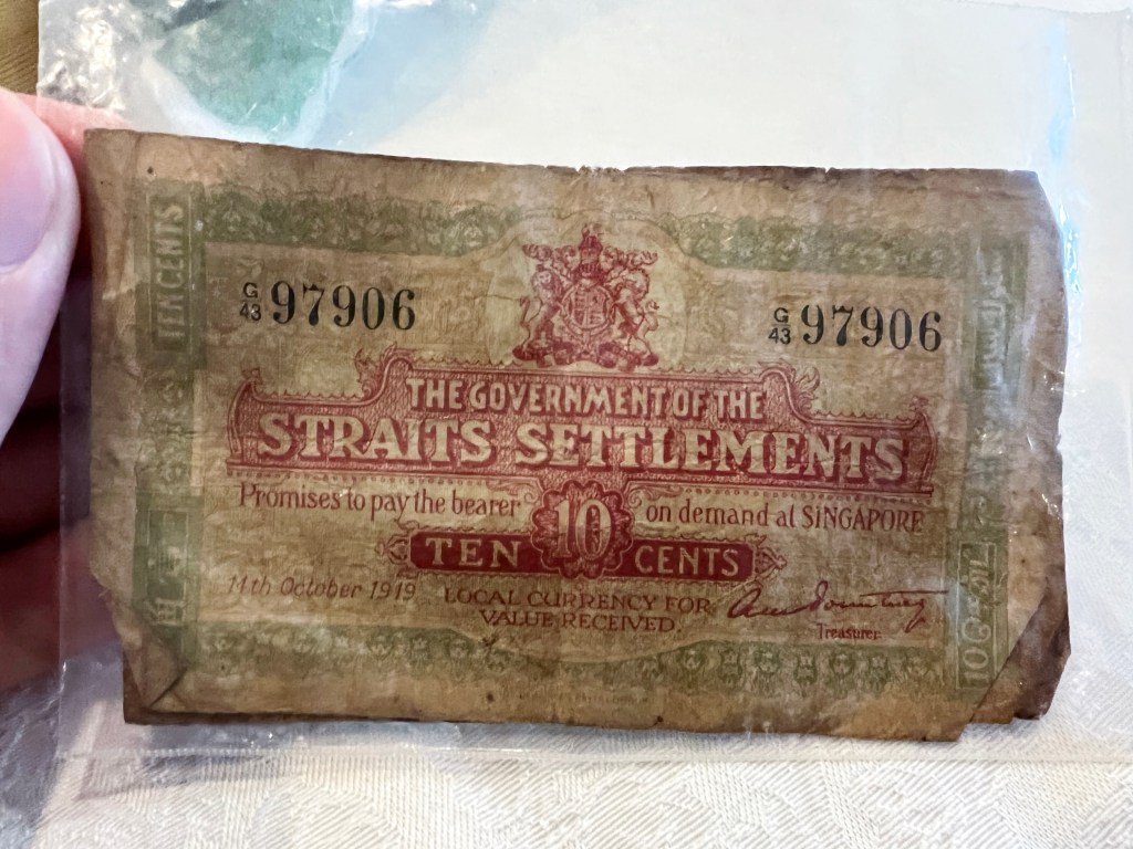 Paper money in a clear plastic sheath. It reads: The Government of the Straits Settlements promises to pay the bearer ten cents on demand at Singapore. Local currency for value received. 11th October 1919.